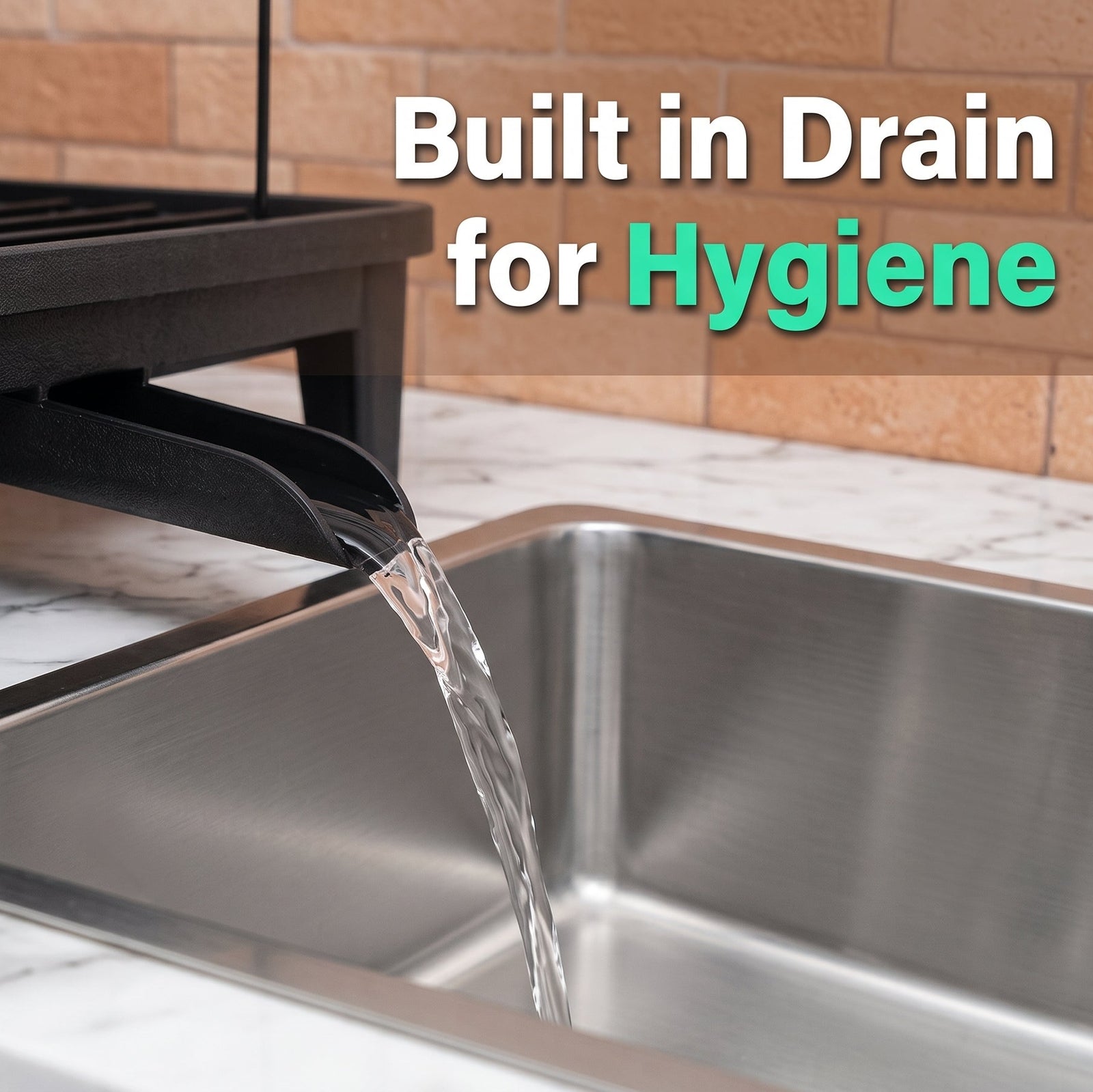 A close-up of a kitchen sink with water flowing from a black built-in drain spout into the sink. A dark dish rack sits above, and the background shows a tan tile wall and white marble countertop.